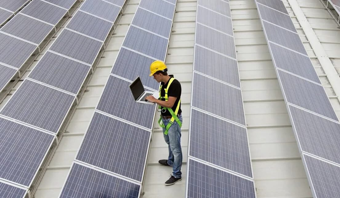 Field technician uses a laptop to verify solar data acquisition system (DAS) points and communications along PV module rows.